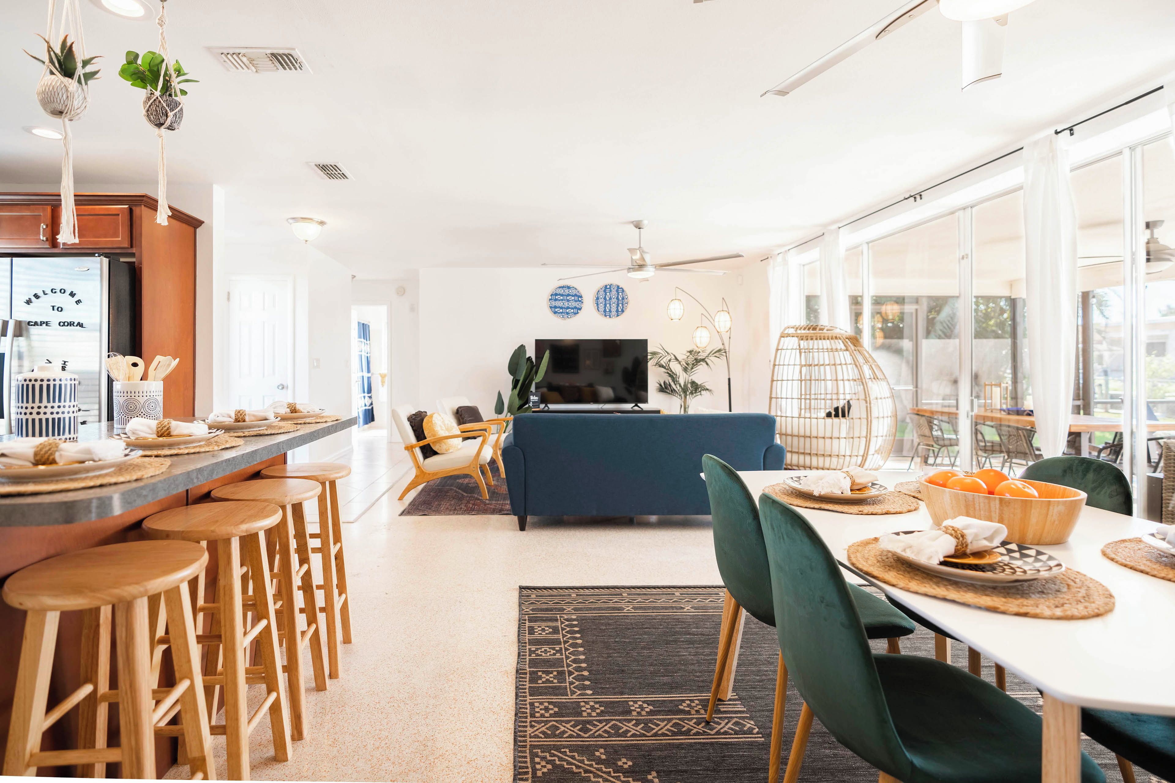 Une cuisine moderne dotée d’un réfrigérateur encastré, de tabourets de bar en bois et d’un coin repas avec une table dressée pour deux personnes.