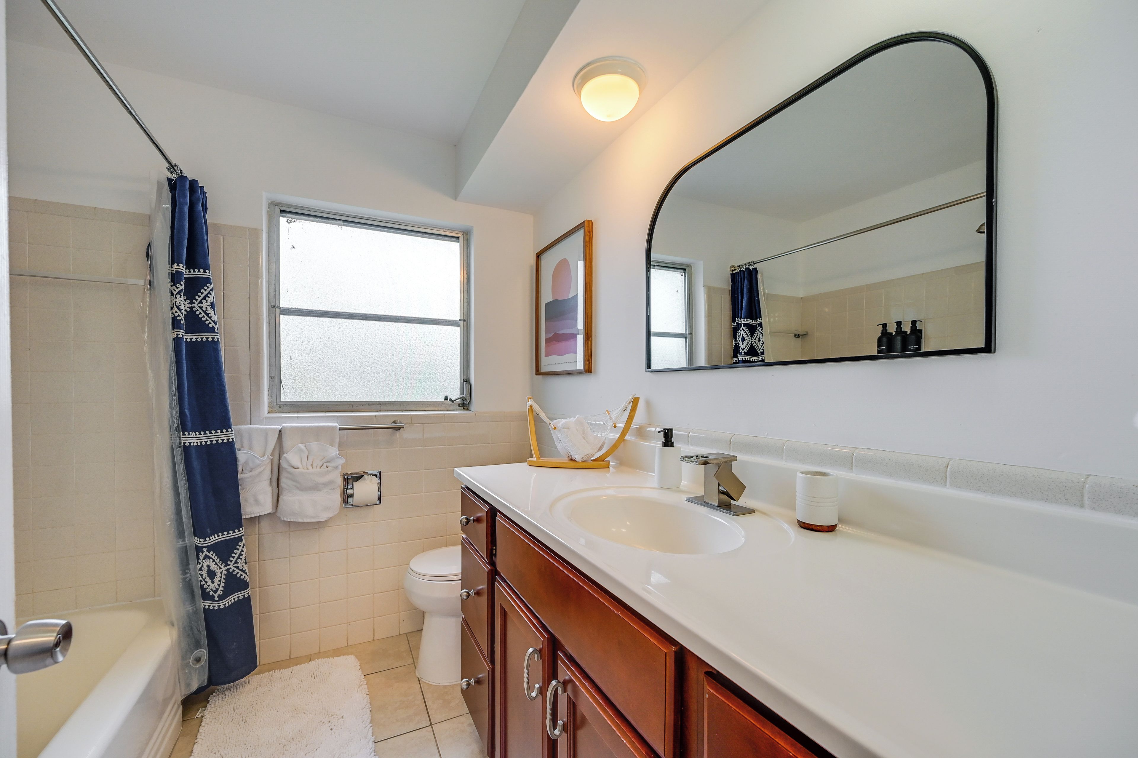 A bathroom with a bathtub, toilet, sink, and a large mirror.