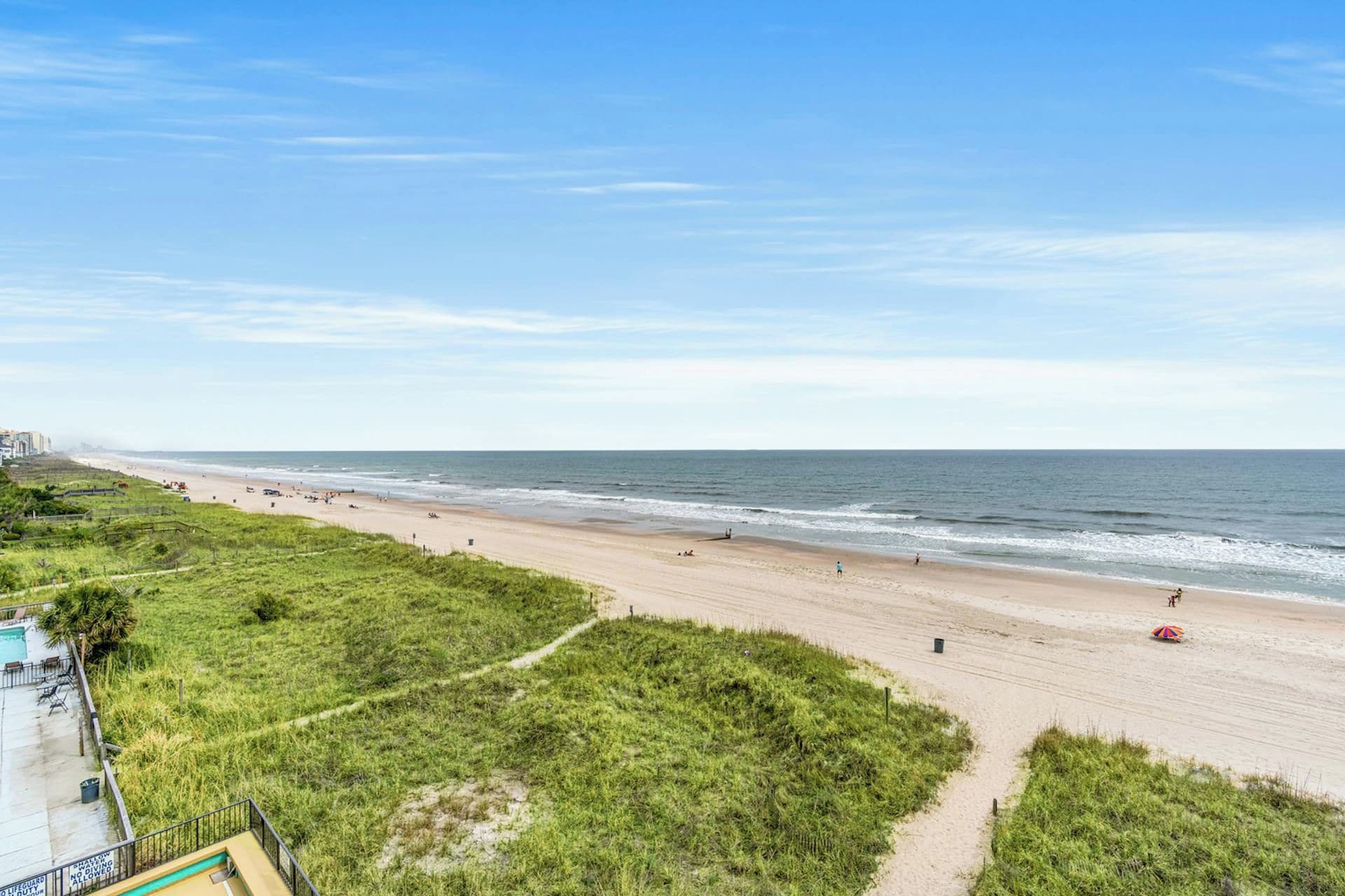 A beach with a clear sky, a sandy shore, and a few people.