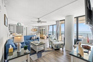 A spacious living room with a large window, a ceiling fan, and a view of the ocean. - 3-bedroom, 2-bathroom, oceanfront condo, Plenty of updates and upgrades | Sea Castle - 3D (North Myrtle Beach)