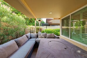 A covered outdoor seating area with a sofa and table, surrounded by greenery and a building with a tiled roof. - 5 Mi to Hospital! Chandler Extended Stay (Chandler)