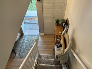 Un escalier avec une rampe, un plancher en bois, un tapis à motifs et une porte à panneaux ajourés.