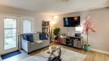 A living room with a sofa, coffee table, TV, bookshelf, and a potted plant.