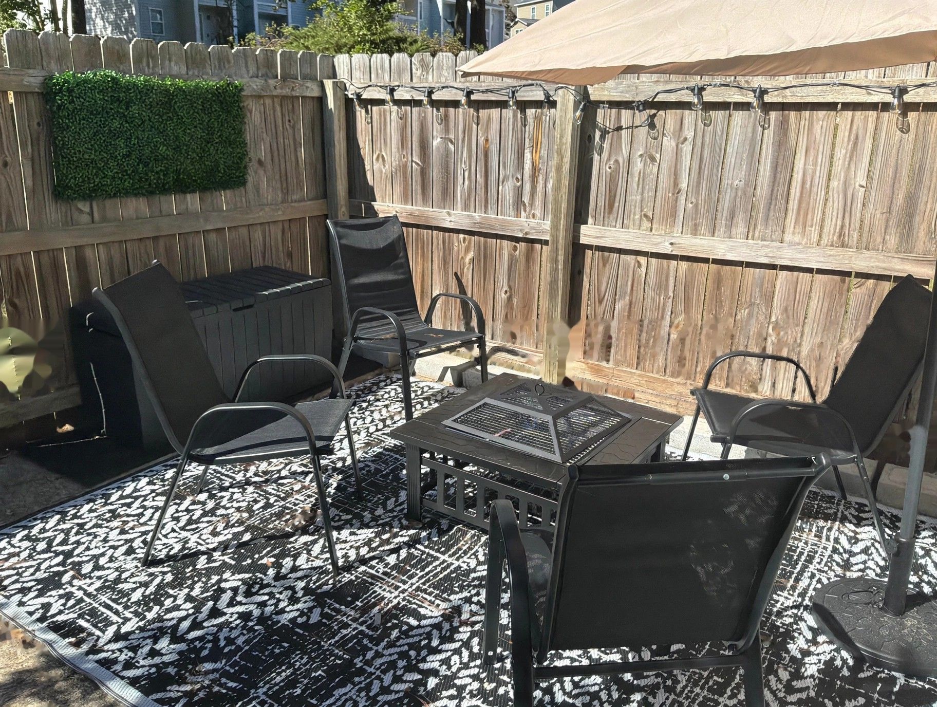 A patio with a grill, chairs, and a patterned rug.