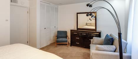 Une chambre à coucher avec un lit, une chaise, une commode, un miroir et une lampe.