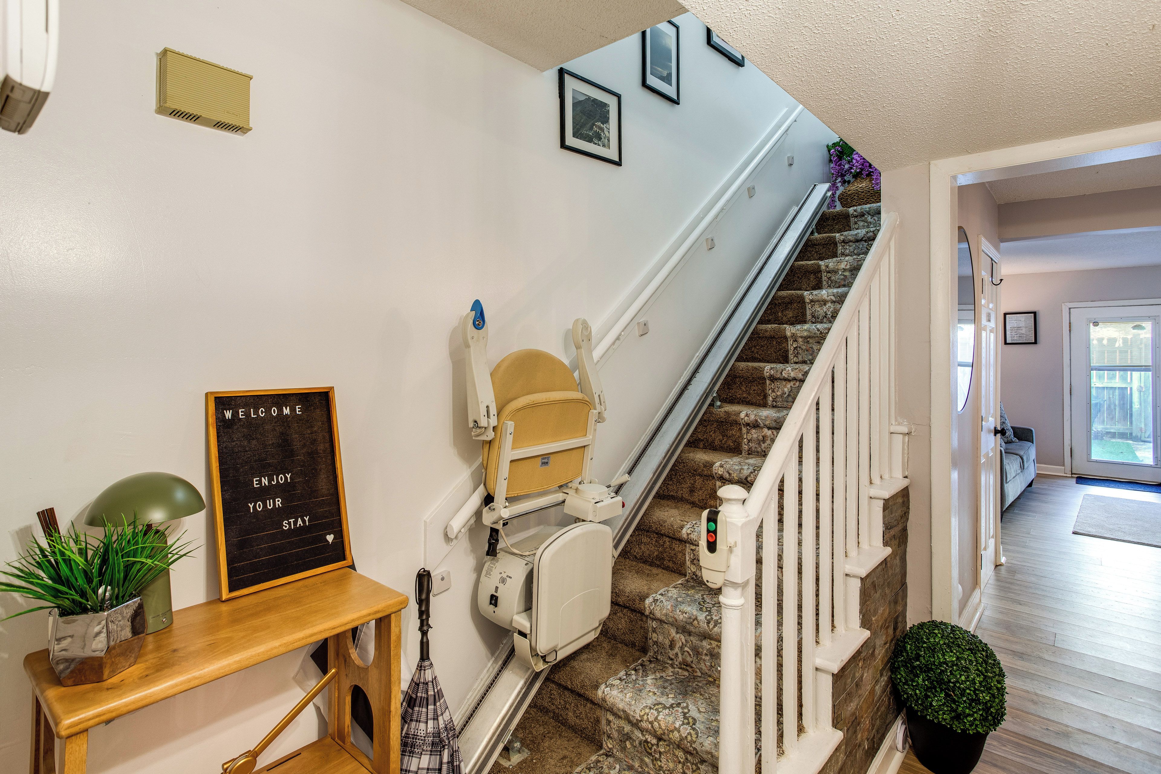 A staircase with a handrail, a wall-mounted sign, and a door leading to another room.