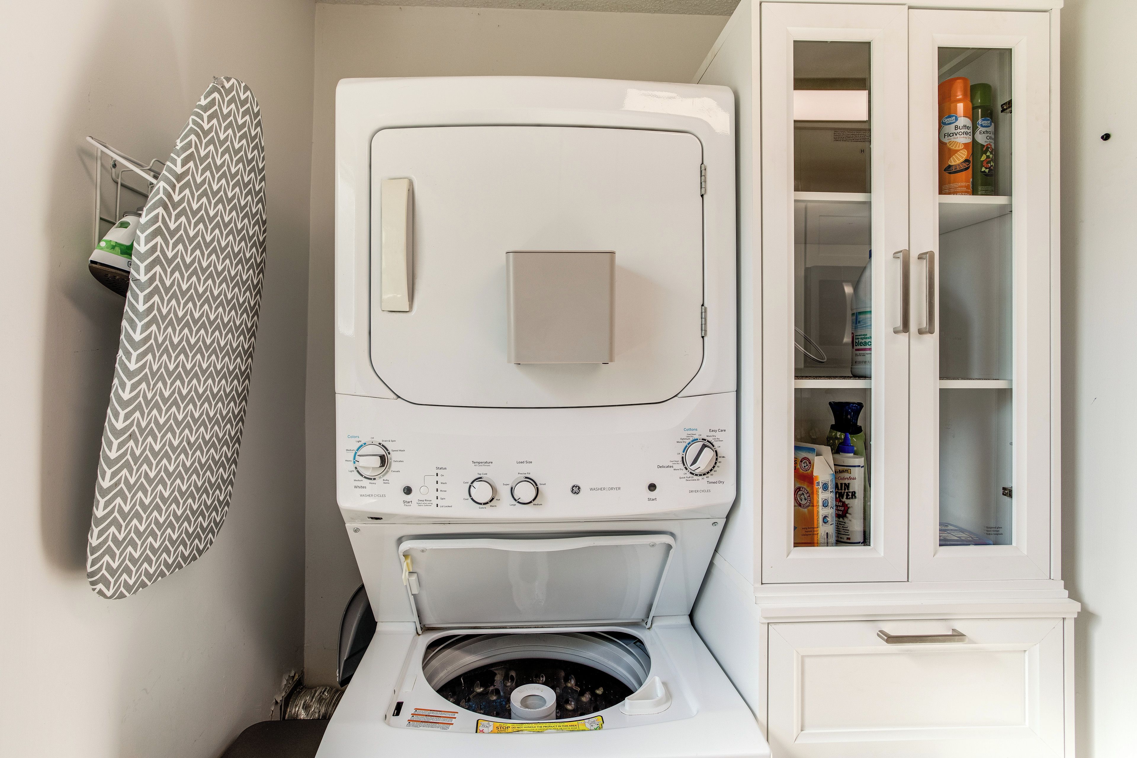 A compact laundry room with a washing machine, dryer, and storage cabinet.