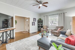 Uma sala de estar com sofá, poltronas, mesa de centro e televisão.