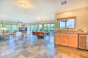 A spacious kitchen with a large island, a dining area with a table and chairs, and a view of the mountains through large windows. - Sedona Serenity: Group-friendly Compound w/ Views! (Sedona)
