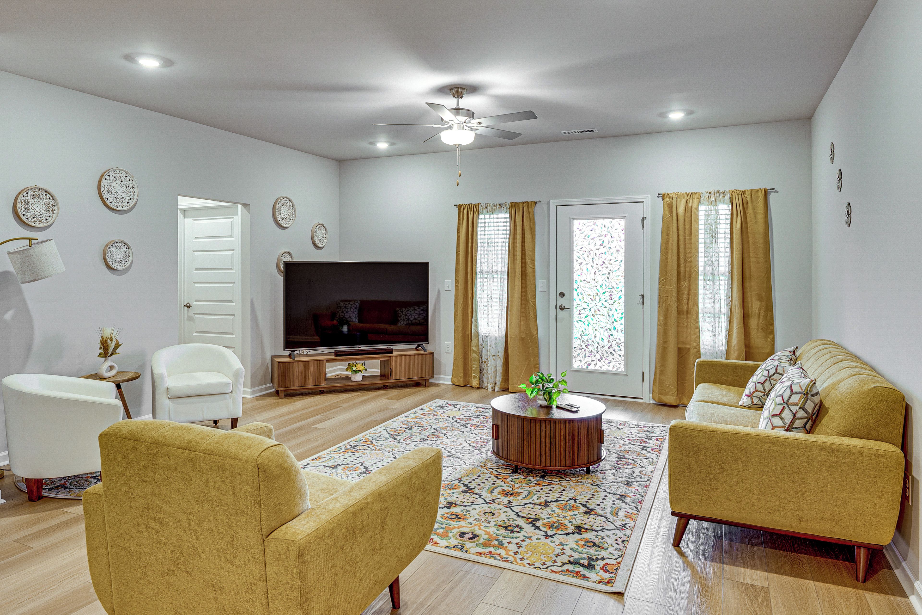 A living room with a flat-screen TV, two sofas, a coffee table, and a patterned rug.