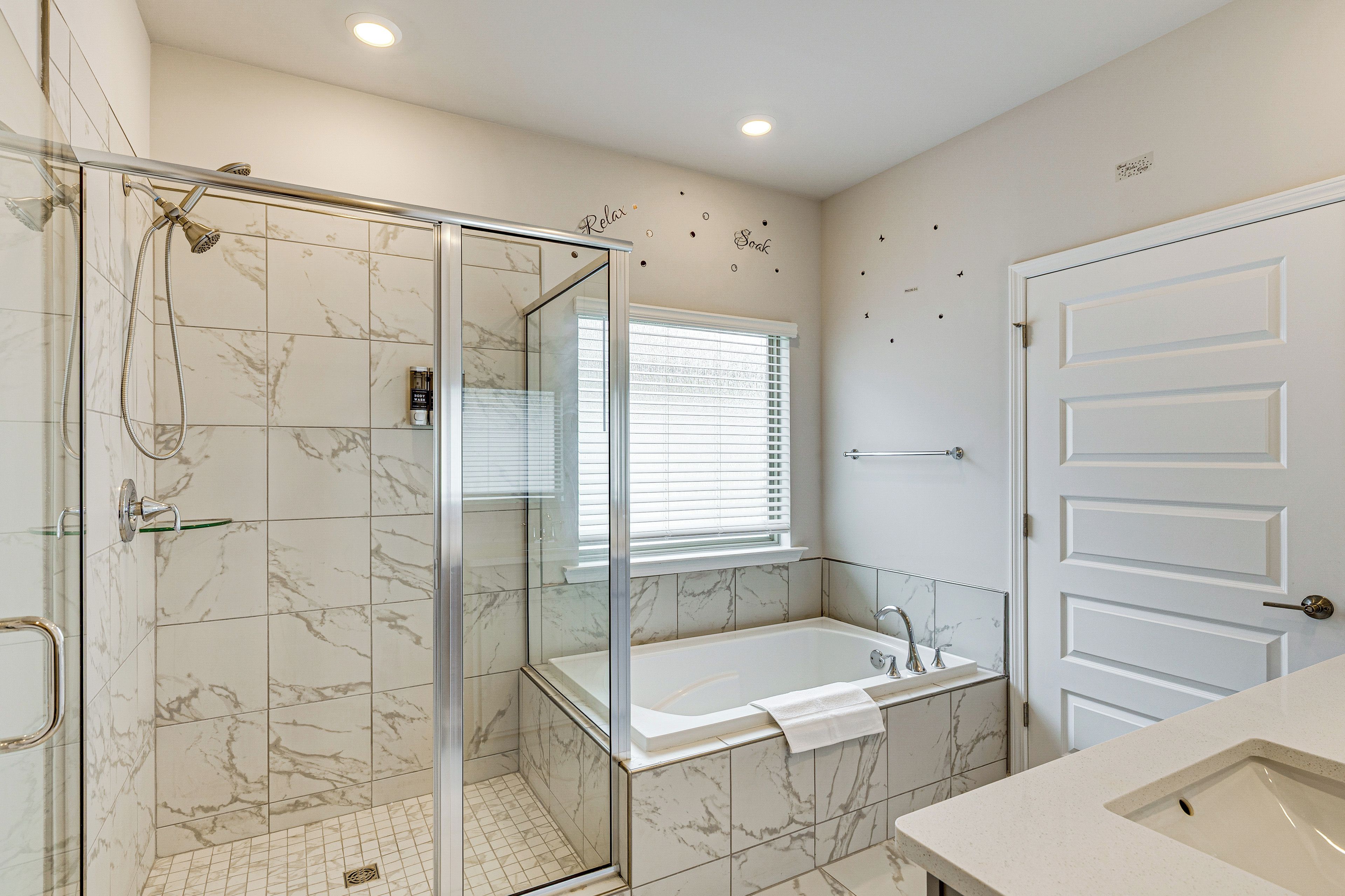 A bathroom with a glass-enclosed shower, a bathtub, and a sink.