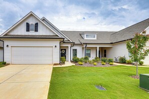 A residential house with a garage, a front porch, and a well-maintained lawn. - Screened Porch: Newly Built Townhome in Madison (Madison)