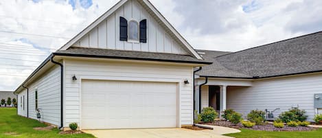 Une maison de plain-pied avec un garage, un toit en pente et un jardin aménagé à l’avant.