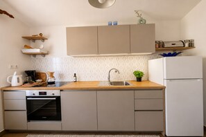 A modern kitchen with a Bosch oven, a sink, wooden countertops, and built-in cabinets. - Seafront apartment with terrace, 4 bedrooms and mooring (Rogoznica)
