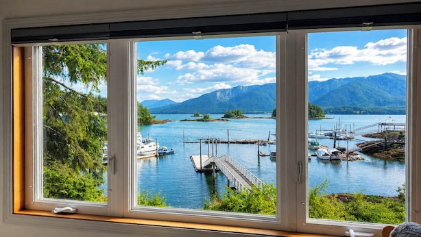 A room with a large window overlooking a lake with boats and a dock. - Ketchikan Oceanfront Retreat Dock On-site, Beach (Ketchikan)