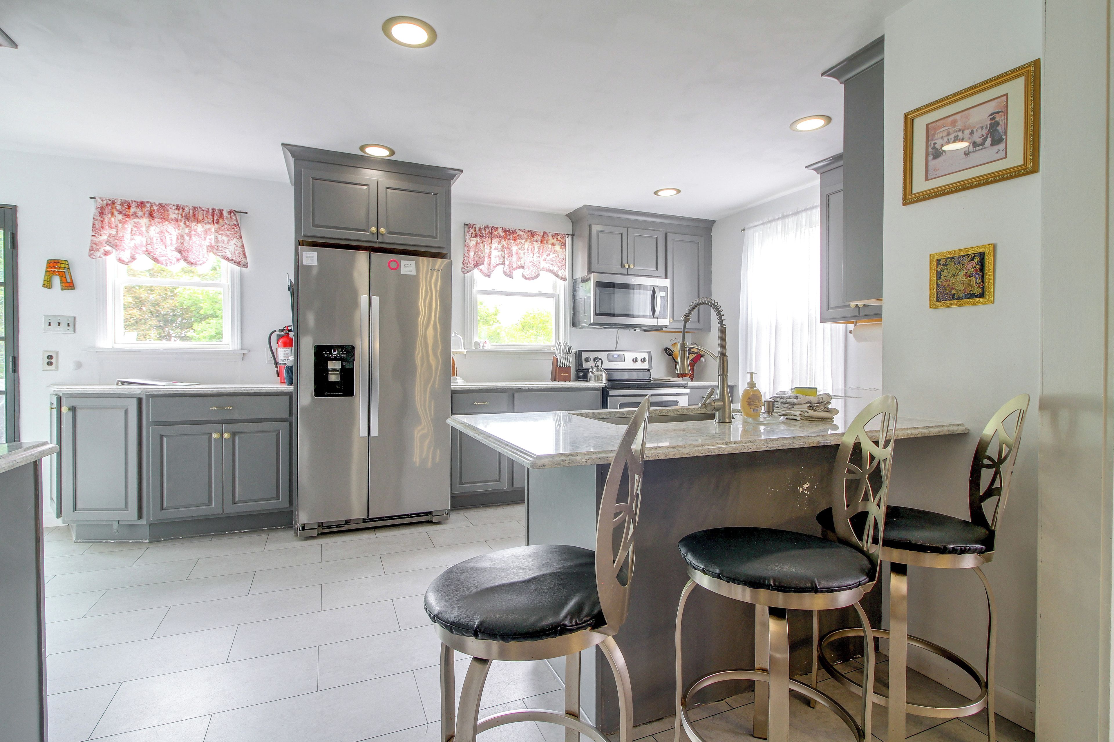 A modern kitchen with grey cabinets, stainless steel appliances, and a central island with bar stools.