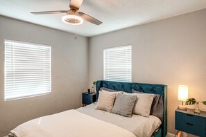 A bedroom with a bed, nightstands, a lamp, and a ceiling fan.