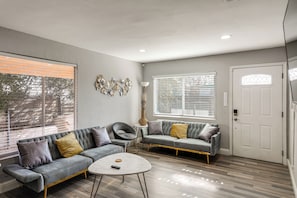 A modern living room with a grey sofa, a round coffee table, and a decorative wall piece.