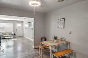 A modern living room with a sofa, coffee table, and a dining area with a table and bench.