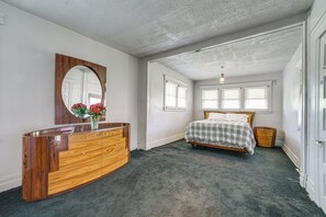 Una camera da letto con una cassettiera in legno, un letto con copriletto a quadri e uno specchio grande.