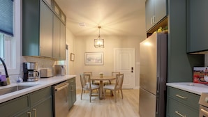 Cozinha compacta com área de refeições, equipada com eletrodomésticos modernos e um lustre.