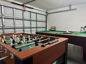 A room with a foosball table, a pool table, and a bicycle. - Ref 301. 3 Bedroom villa own pool. Lake Berkley Resort. (Osceola County)