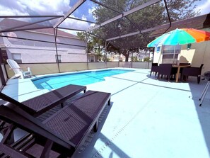 Une piscine extérieure couverte, dotée de chaises longues et d’une table.