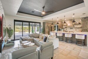A spacious living area with a large sofa, a coffee table, and a dining bar with bar stools. - Outdoor Oasis! Luxe Waterfront Gem in Lehigh Acres (Lehigh Acres)