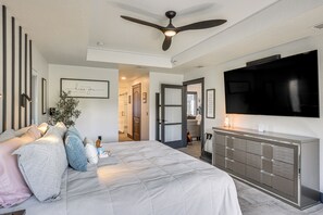 A modern bedroom with a bed, a ceiling fan, a TV, and a dresser. - Outdoor Oasis! Luxe Waterfront Gem in Lehigh Acres (Lehigh Acres)