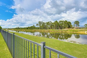 A river with a grassy bank and a metal fence. - Outdoor Oasis! Luxe Waterfront Gem in Lehigh Acres (Lehigh Acres)
