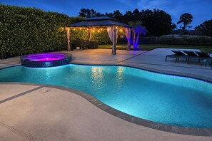 A swimming pool with a hot tub and a covered seating area with string lights. - Outdoor Oasis! Luxe Waterfront Gem in Lehigh Acres (Lehigh Acres)