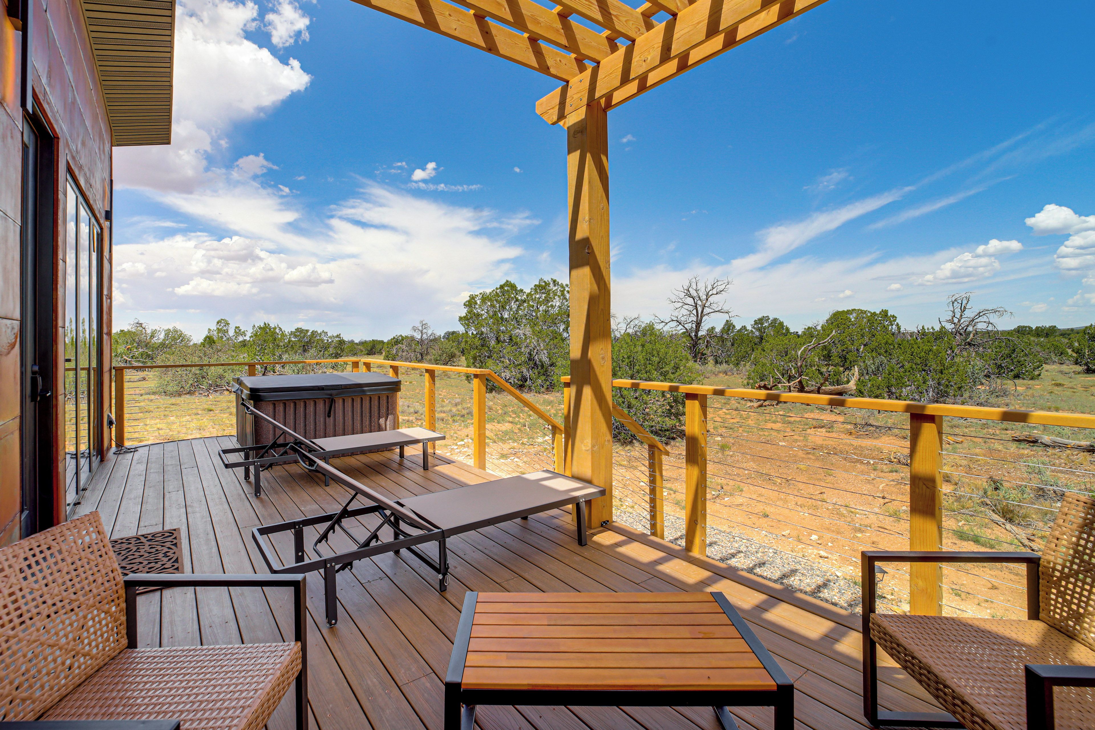 Une terrasse en bois, aménagée avec du mobilier d’extérieur, notamment une table et des chaises, qui offre une vue sur un paysage naturel.