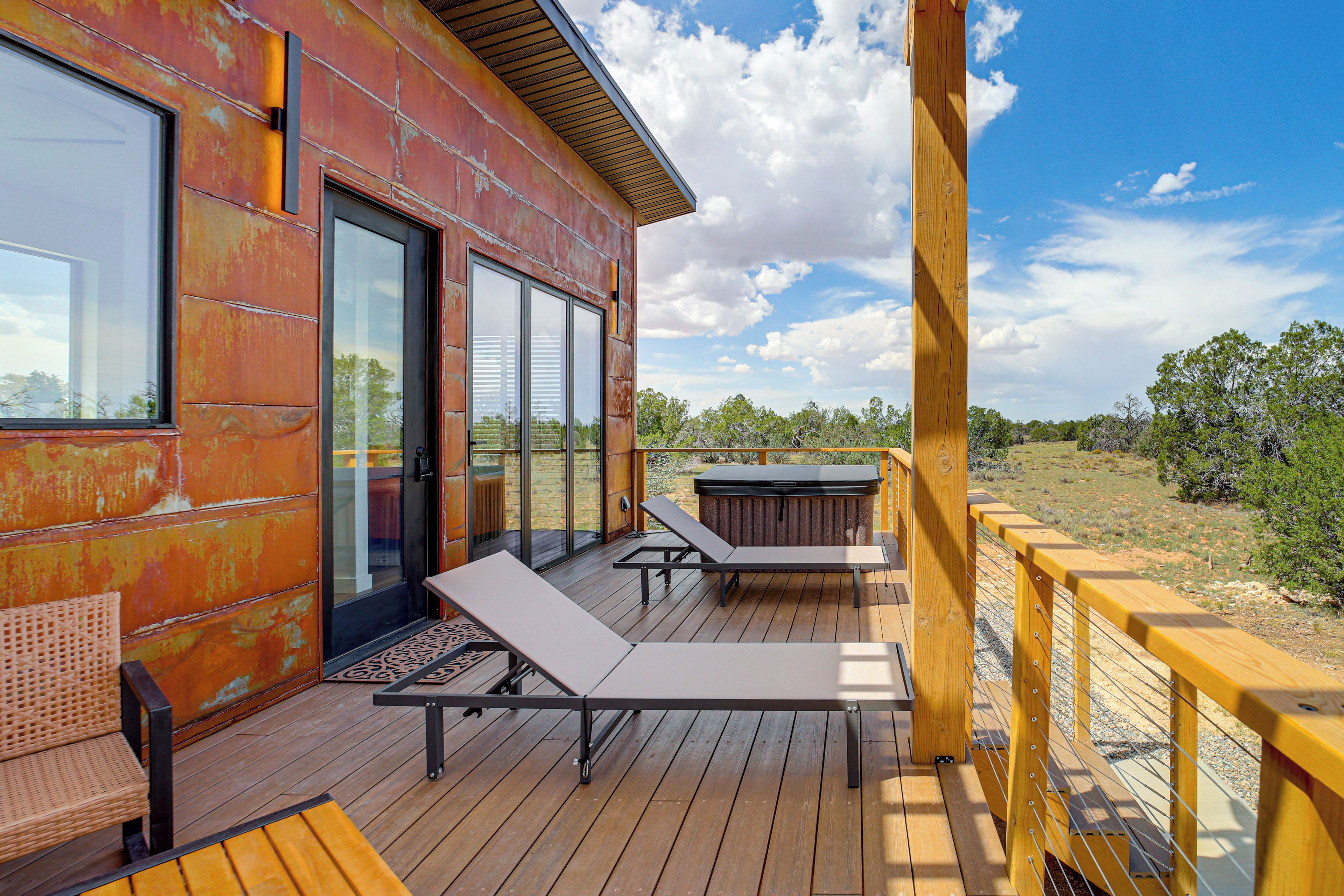 Une terrasse en bois avec des chaises longues, un jacuzzi et une vue sur le paysage environnant.