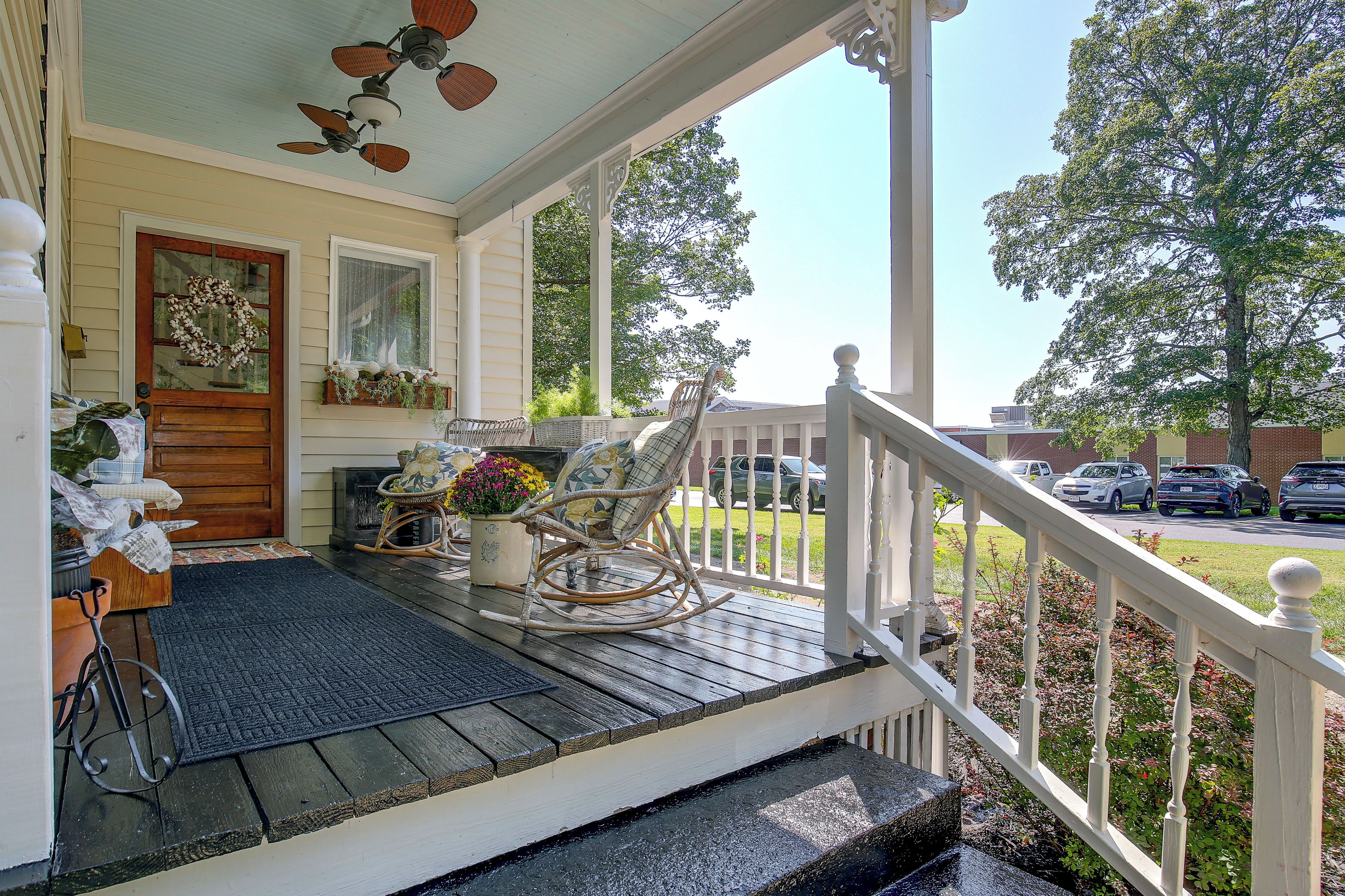 A porch with a rocking chair, a potted plant, and a door with a wreath.