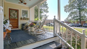 A porch with a rocking chair, a potted plant, and a door with a wreath. - Shop, Dine, Explore Dtwn! Walkable Farmington Home (Farmington)