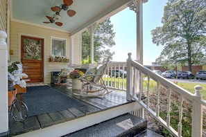 A porch with a rocking chair, a potted plant, and a door with a wreath. - Shop, Dine, Explore Dtwn! Walkable Farmington Home (Farmington)