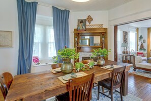 A dining room with a wooden table, chairs, and potted plants.