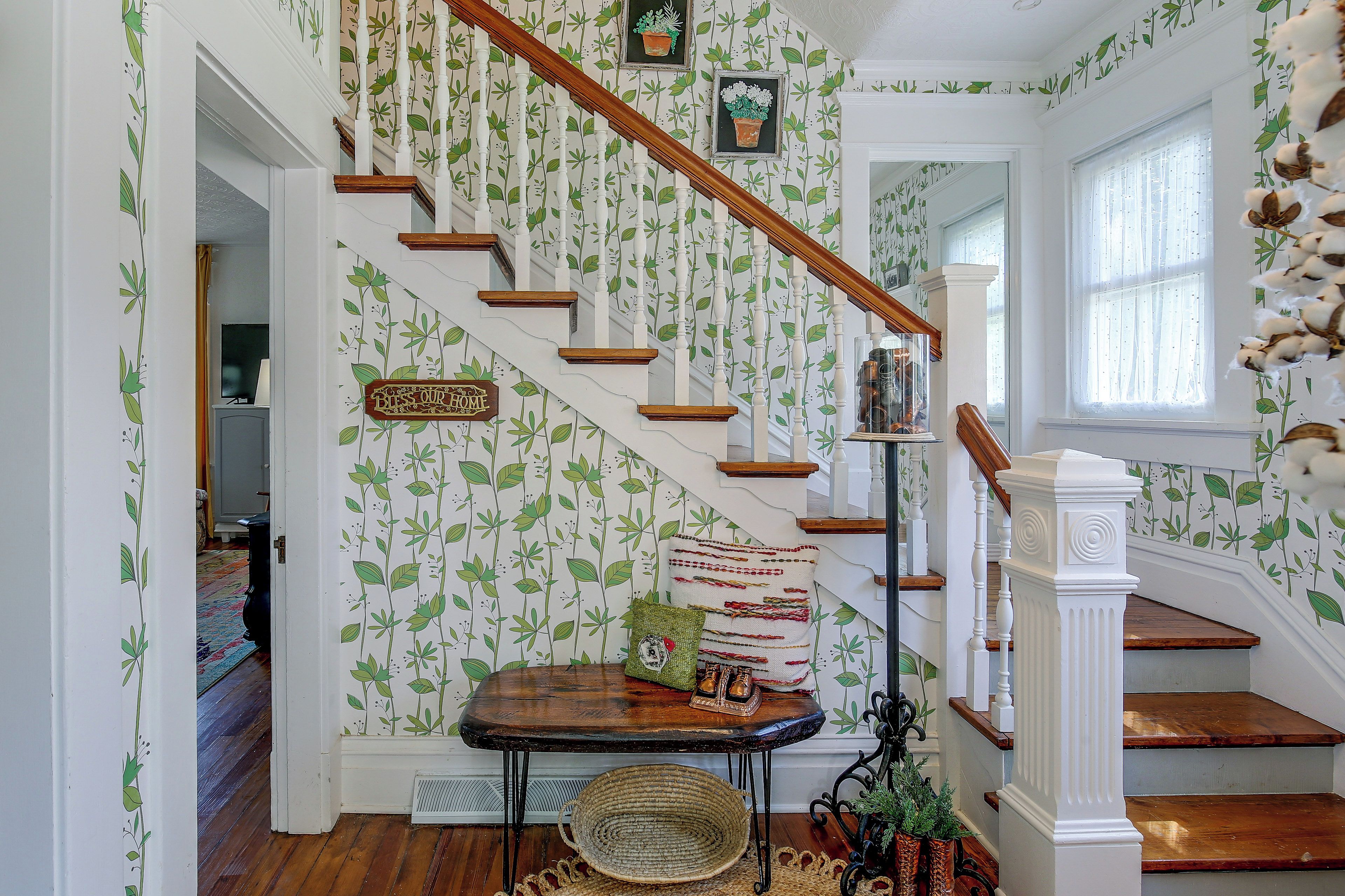 A staircase with a floral wallpaper design, a wooden handrail, and a small table with decorative items.