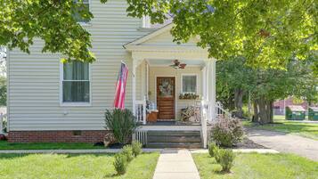 A two-story house with a front porch, a flag, and a mailbox.