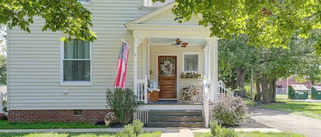A two-story house with a front porch, a flag, and a mailbox.