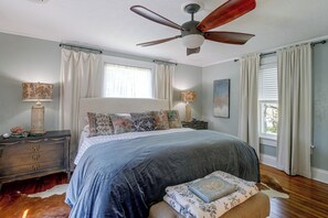 A bedroom with a bed, nightstands, a ceiling fan, and a window with curtains.