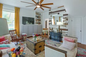 A living room with a television, bookshelves, a blue dresser, and a ceiling fan. - Shop, Dine, Explore Dtwn! Walkable Farmington Home (Farmington)