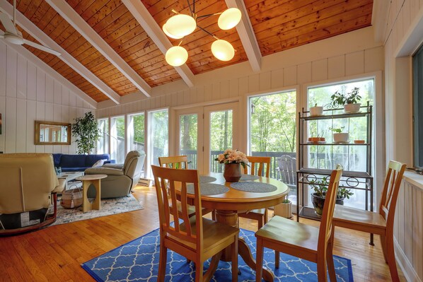 A room with a wooden ceiling, a dining table with chairs, a sofa, and a window with a view of trees. - Long-range Views in Gated Wolf Laurel/ski/ashville (Mars Hill)