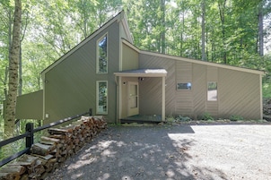 A single-story cabin with a sloped roof, a front porch, and a stone wall.