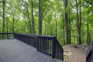 A wooden deck with a railing overlooking a forested area.