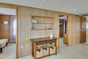 Una habitación con paredes de madera panelada, un escritorio de madera con un espejo, un banco y cestas de mimbre.