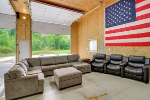 Quarto com sofá seccional, poltronas de couro e uma grande bandeira americana.