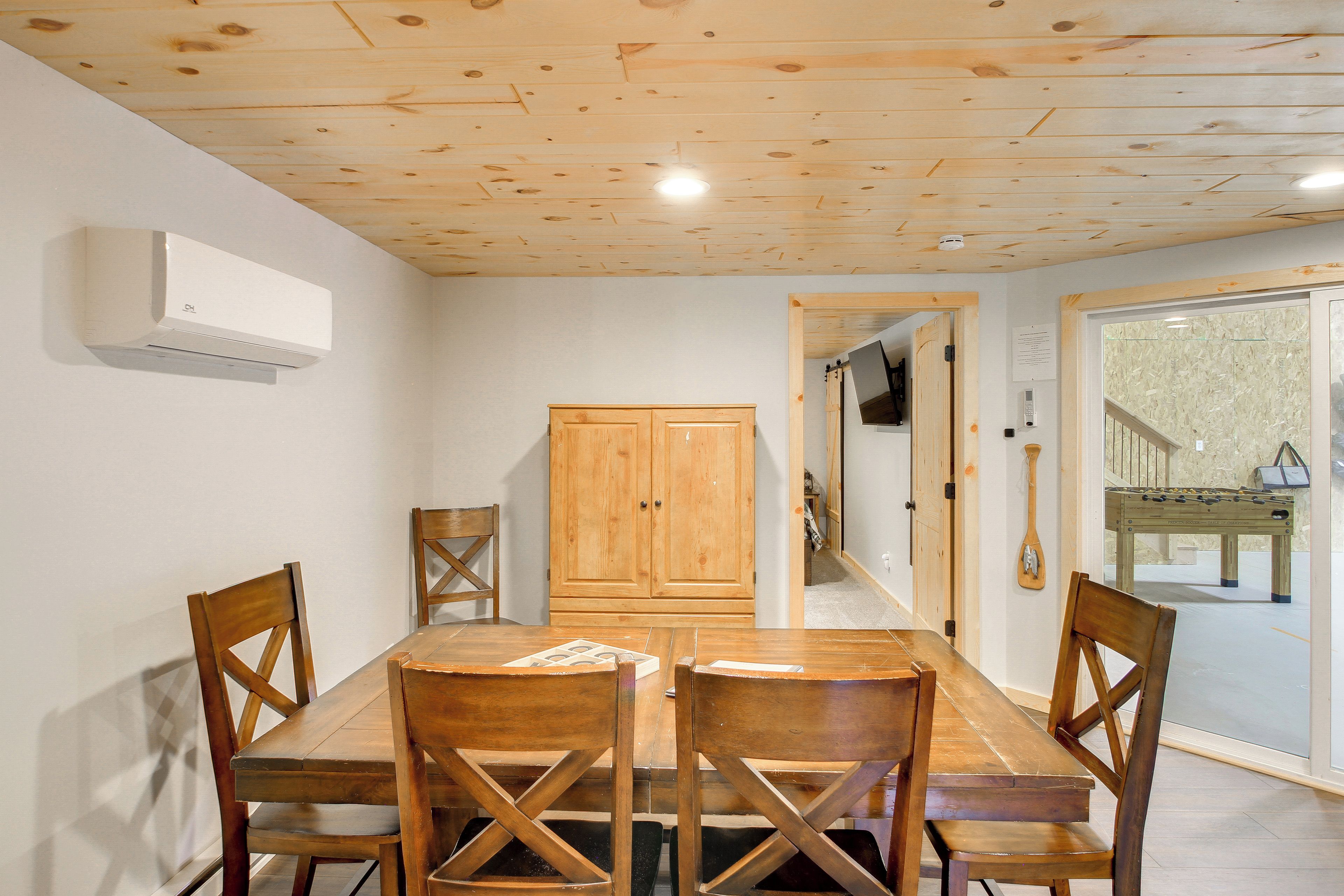 A dining area with a wooden table and chairs, a wooden cabinet, and a door leading to another room.