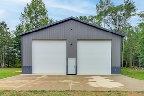 A two-story metal building with a garage door and a small door, surrounded by trees. - 'riverside Escape' Ride, Paddle, Relax (Crosby)