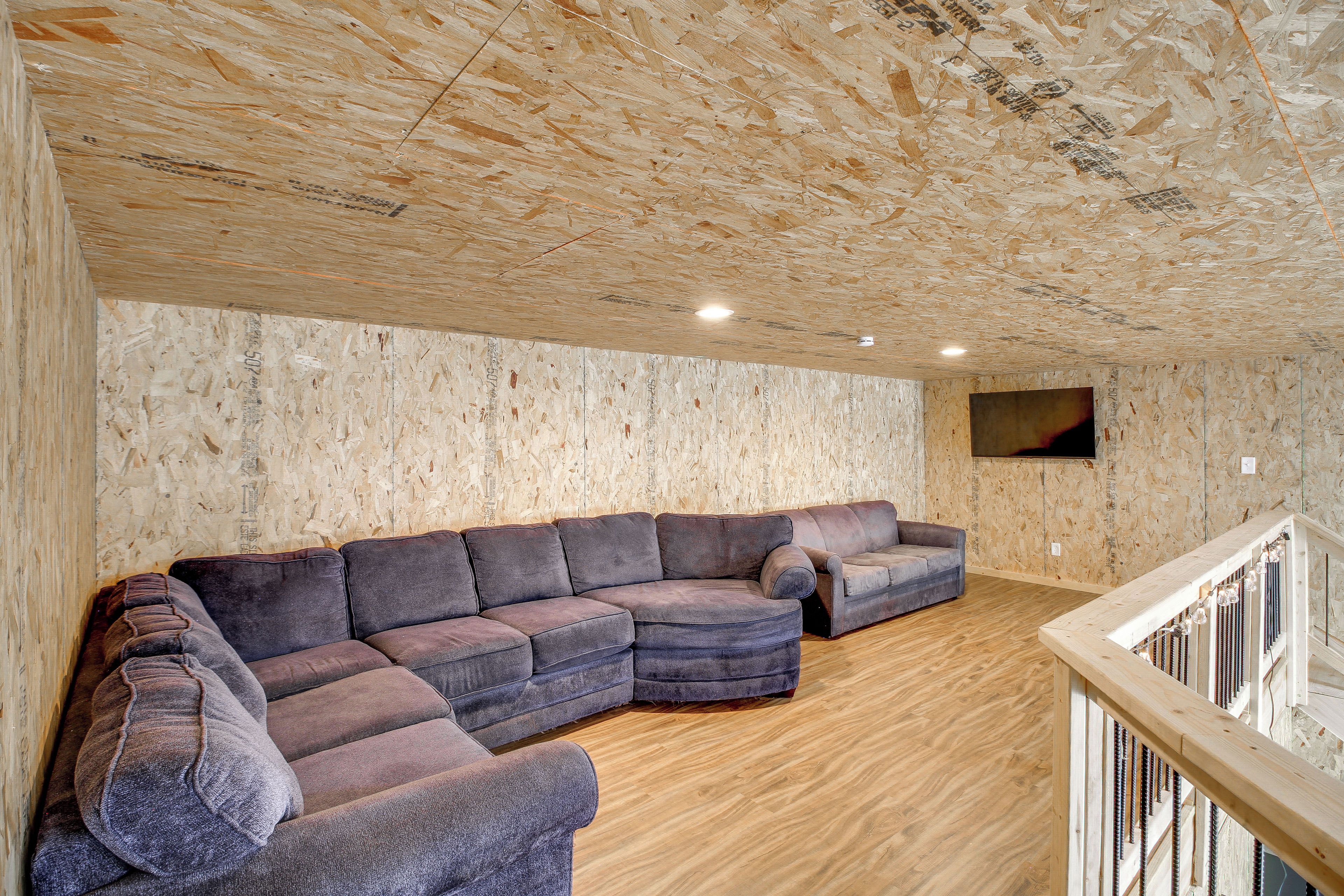 Ein Zimmer mit einer Eckcouch, Holzböden und einem an der Wand montierten Fernseher.